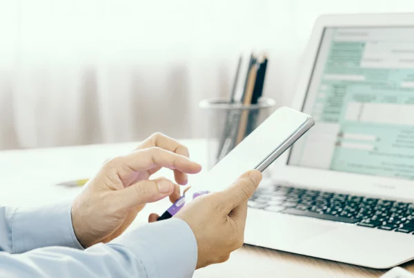 person holding phone in front of computer